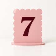 Blush pink scalloped acrylic table number 7 with raised burgundy numeral and matching base