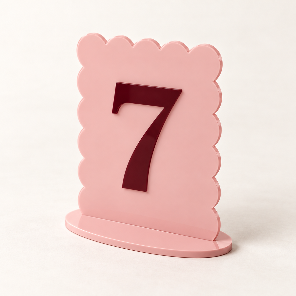 Angled view of blush pink scalloped acrylic table number 7 and matching base